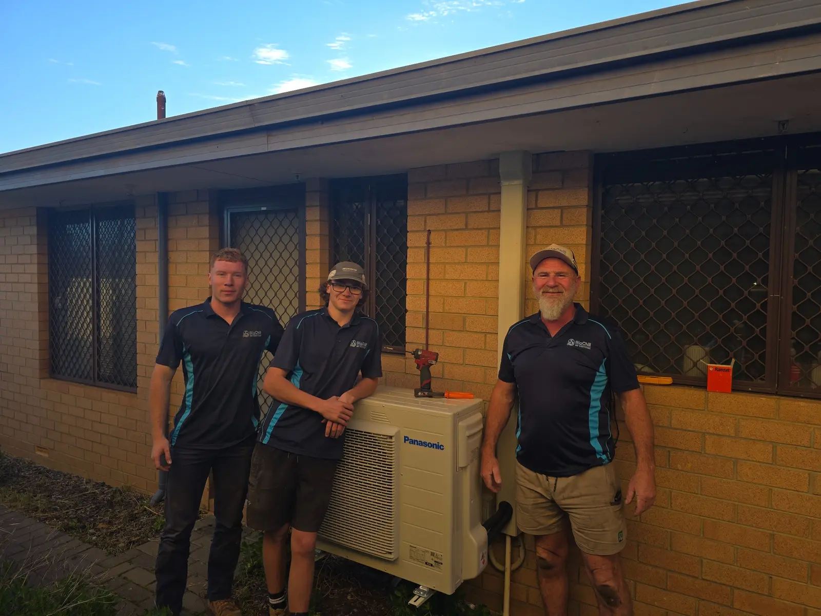 Three Big Chill team members beside a newly installed outdoor air conditioning unit